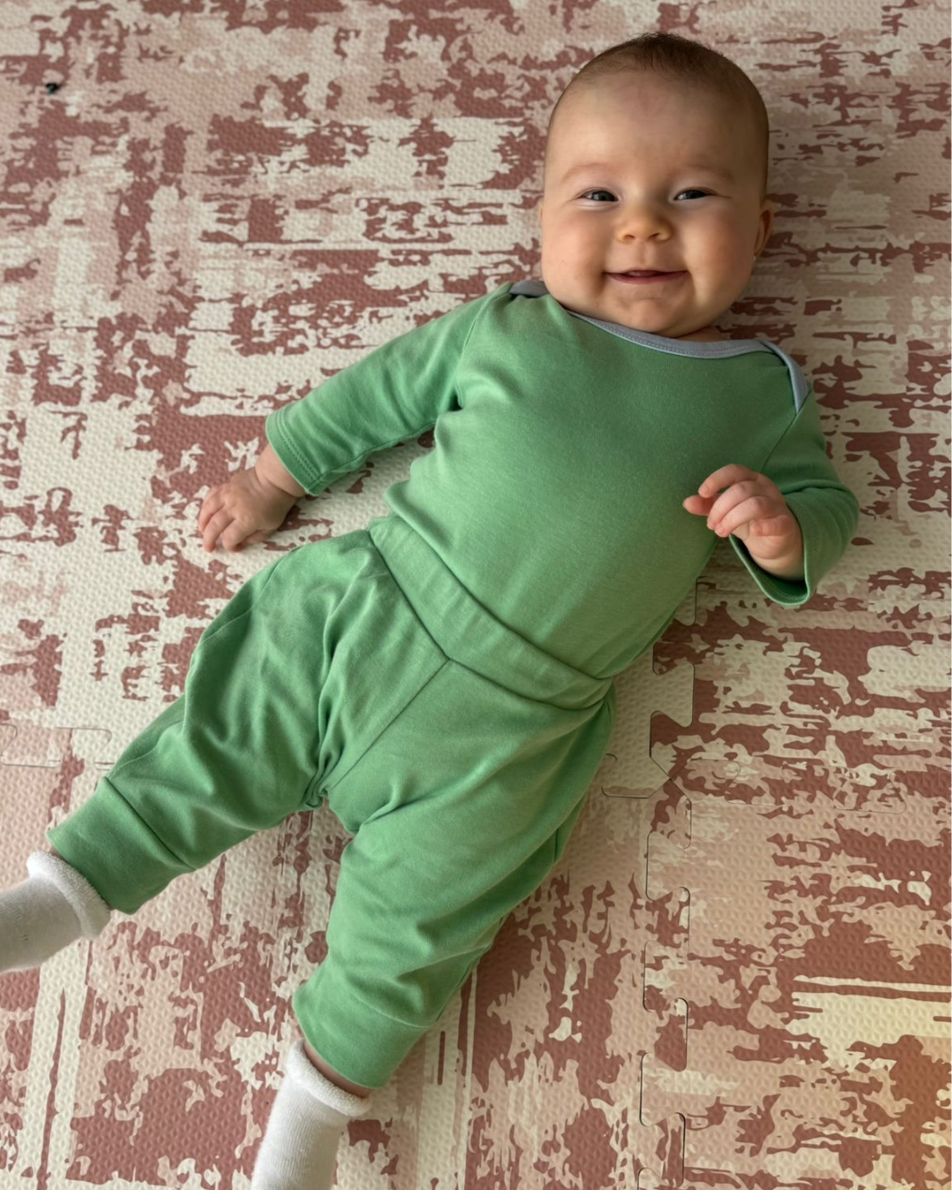 Grass Green with Blue | Baby in a green outfit lying on a textured surface
