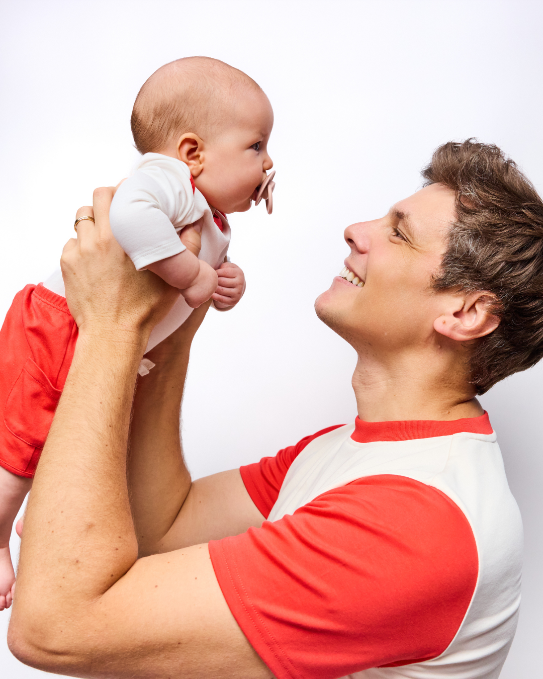 Dad holding baby matching in red and white tshirt and bodysuit peruvian pima cotton