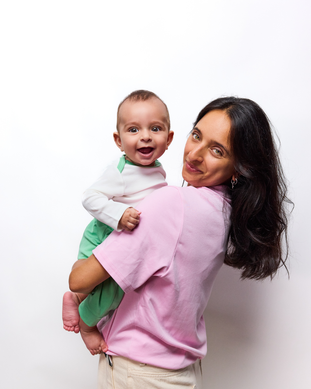 Adult Solid Tshirt Pink holding Baby in Long Sleeve bodysuit and green jogger pants