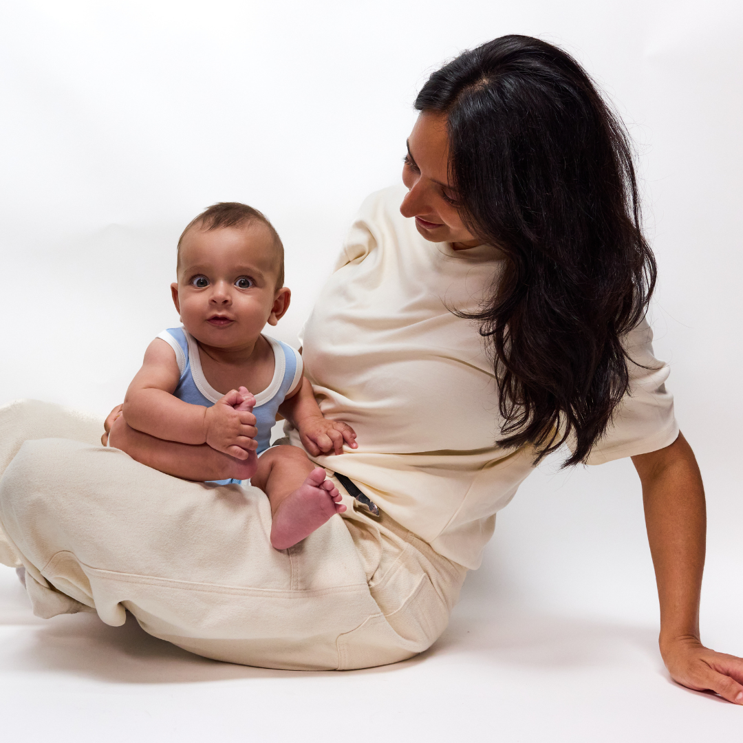 White | Woman holding a baby wrapped in a white wrap against a white background