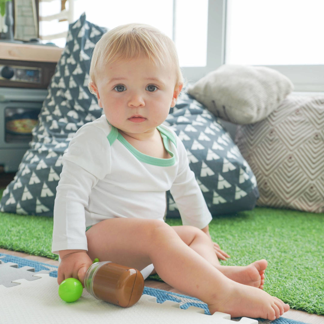 Baby wearing the long sleeve onesie or bodysuit in white with grass green made with peruvian pima cotton