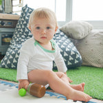 Baby wearing the long sleeve onesie or bodysuit in white with grass green made with peruvian pima cotton