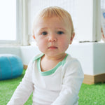 Baby wearing long sleeve bodysuit in white with grass green made with peruvian pima cotton