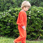 Engine Red; Engine Red with Pink | Child in an red outfit standing on grass with green bushes and white flowers in the background