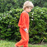 Engine Red; Engine Red with Pink | Child in an red outfit standing on grass with green bushes and white flowers in the background