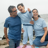 Light Blue | Family of three standing on a beach with a child on a pink and blue float.