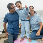 Light Blue | Family of three standing on a beach with a child on a pink and blue float.