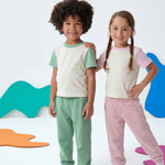 Grass Green; Pink | Two children wearing matching outfits with colorful abstract shapes in the background