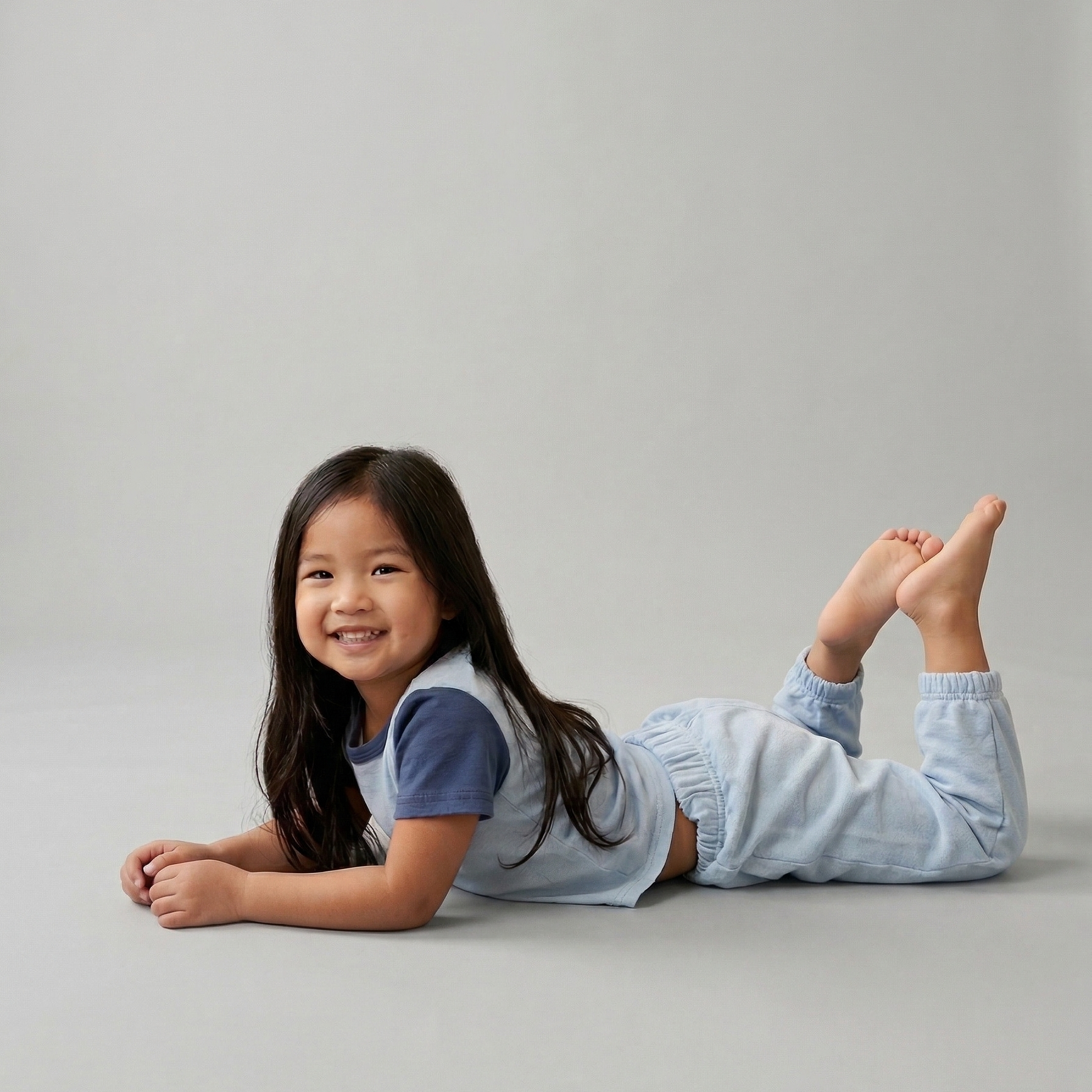 Light Blue, Light Blue with Navy Blue | Young girl lying on a gray surface wearing a Play Set with tshirt and sweatpants