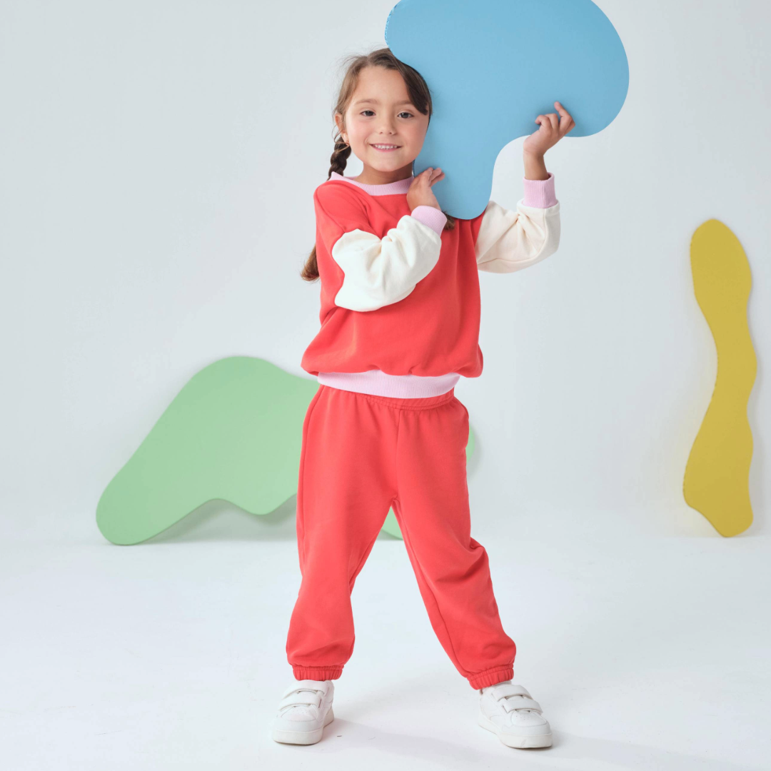 Engine Red | Child wearing a red outfit holding a blue speech bubble-shaped object against a white background