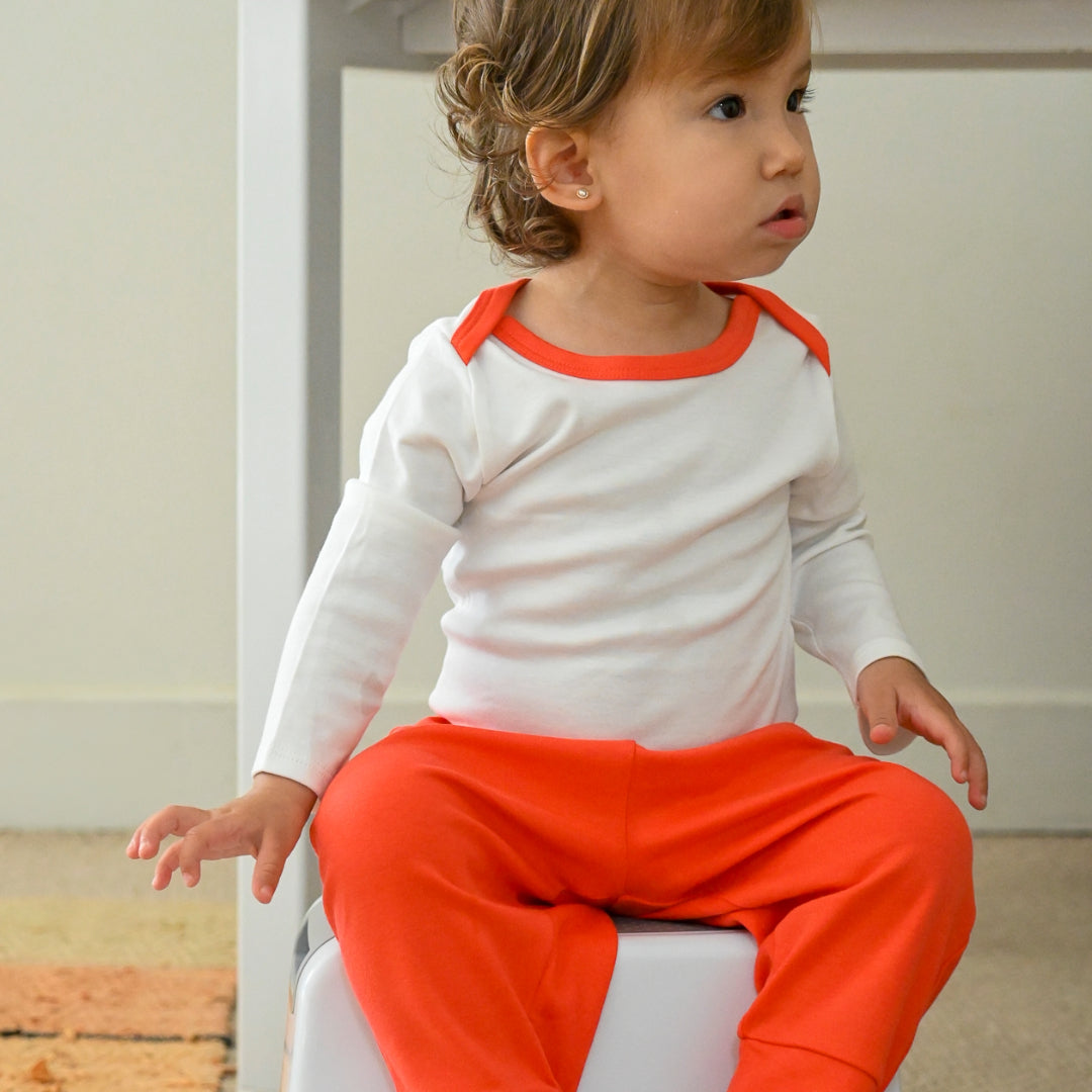 Baby wearing long sleeve bodysuit and jogger pants in white with red made of 100% peruvian pima cotton