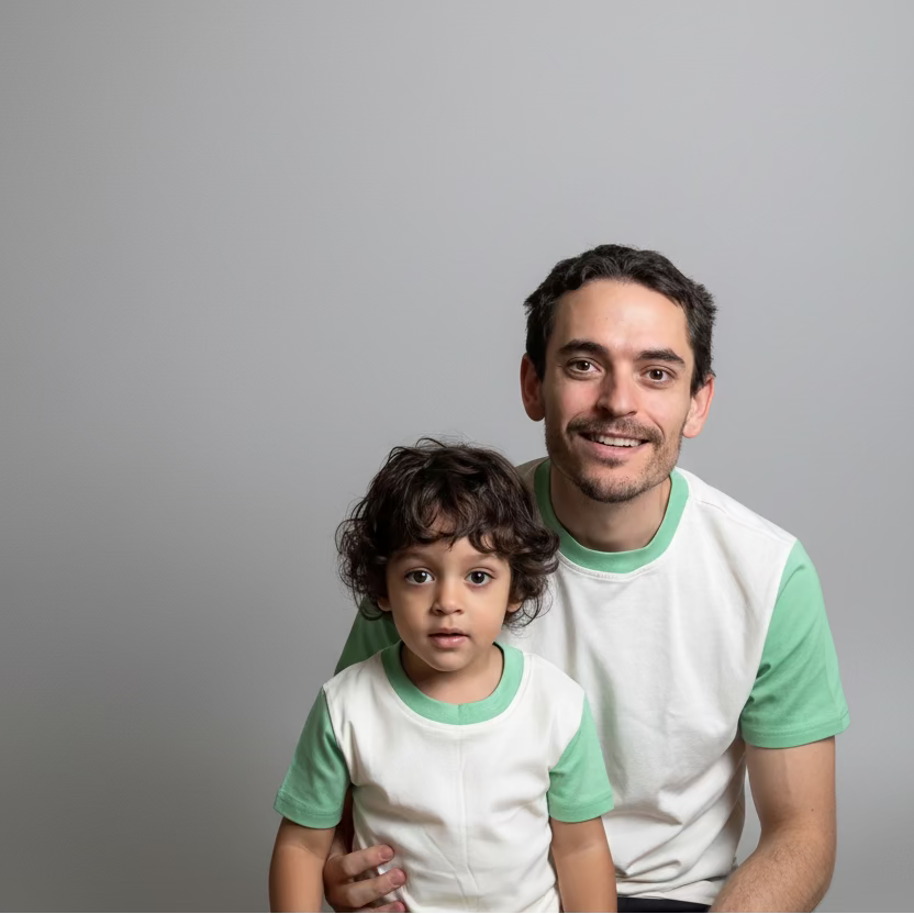 White with Green Grass | Man and child in matching green and white shirts sitting together in a room.