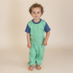 Grass Green with Navy Blue | Child wearing a green outfit standing on wooden stairs